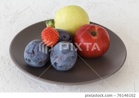 Just picked plums, apples and strawberry on the plate 76146102