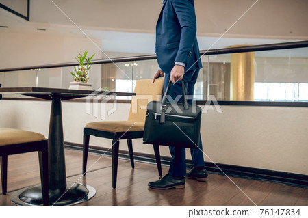 Buisnessman in a blue suit with a black suitcase 76147834