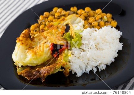 Chicken thighs with cabbage leaves in batter, cheakpea and rice at plate 76148804