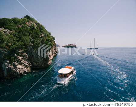 A pleasure boat sails to the island of Sveti Stefan in Montenegro. A pleasure boat sails to the island of Sveti Stefan in Montenegro. 76149790