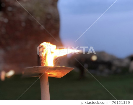 A torch fire burning in front of the ruins of an old castle A torch fire burning in front of the ruins of an old castle 76151359