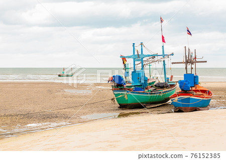 pair of fishing boats stand on a shallow against the low tide of the ocean with copy space pair of fishing boats stand on a shallow against the low tide of the ocean with copy space 76152385