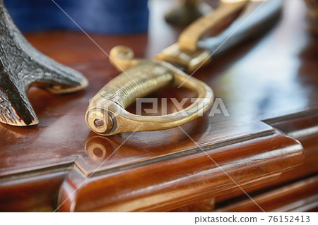 Saber naval officer with a gold pen on a wooden background Saber naval officer with a gold pen on a wooden background 76152413