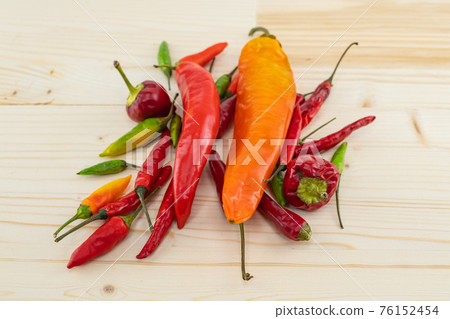 pair of large hot peppers orange and red on a background of chili and wooden table pair of large hot peppers orange and red on a background of chili and wooden table 76152454