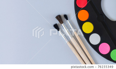 Art palette with paint and brushes top view on gray background Art palette with paint and brushes top view on gray background 76155349