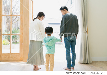 在陽光明媚的日子裡看著露台的年輕家庭（後視圖） 76156120