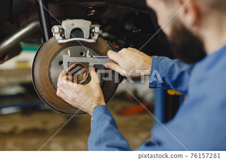 Man replaces wheel in car in garage on hoist 76157281