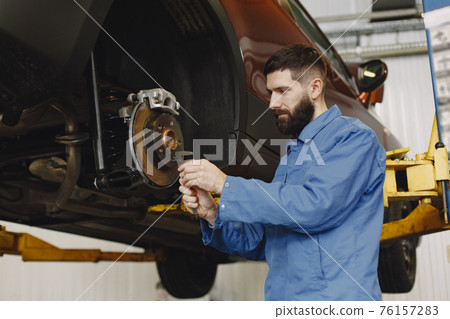 Man replaces wheel in car in garage on hoist 76157283