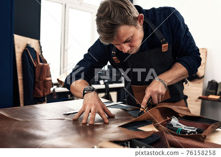 Skilled leather manufacture worker cutting some samples 76158258