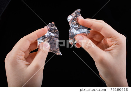 Hand tearing a heart shaped aluminium foil on wooden background Hand tearing a heart shaped aluminium foil on wooden background 76160418