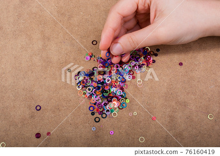 Hand holding decorative shiny colorful confetti on wooden background Hand holding decorative shiny colorful confetti on wooden background 76160419