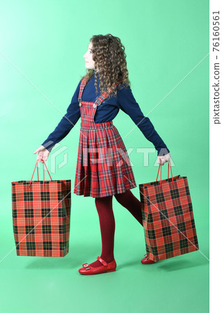 Child with a red packet isolated on green background. Little beauty shopaholic. Holiday present, shopping. Child with a red packet isolated on green background. Little beauty shopaholic. Holiday present, shopping. 76160561