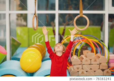 Kids doing exercises in gym at kindergarten or elementary school. Children sport and fitness sports rings concept. 76161241