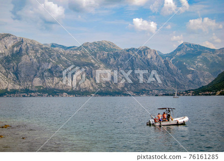 Bay of Kotor on a sunny evening with two unrecognizable men in an inflatable motor boat. Mountains and sea. Beautiful nature. Bay of Kotor on a sunny evening with two unrecognizable men in an inflatable motor boat. Mountains and sea. Beautiful nature. 76161285