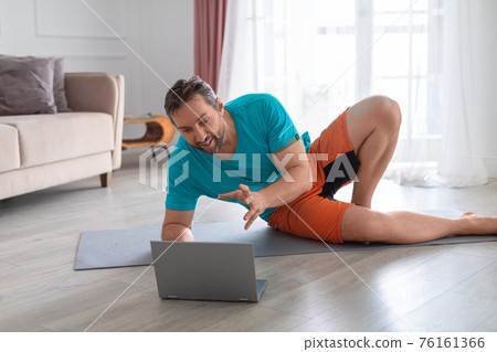 Yoga coach during an online video call. He communicates with the client explaining the exercise and nutritional aspects. Yoga coach during an online video call. He communicates with the client explaining the exercise and nutritional aspects. 76161366