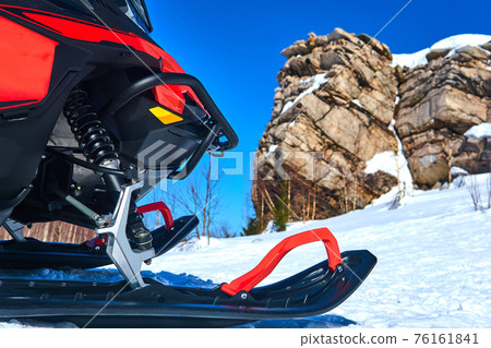 snowmobile in the foreground against a blurred mountain winter landscape snowmobile in the foreground against a blurred mountain winter landscape 76161841