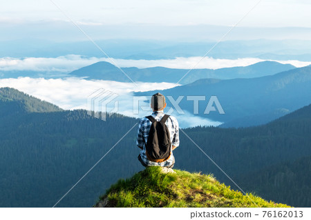 A tourist sits on the edge of a cliff A tourist sits on the edge of a cliff 76162013