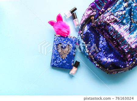 Bright composition of fashion accessories. Glitter sequins backpack, notepad, funny pen, nail polish. Different objects on soft pastel background. Flat lay, top view 76163024