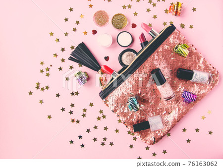 Bright composition of fashion accessories. Glitter sequins cosmetic bag with lipsticks, nail polishes and other objects. Object on soft pastel background with decorative tinsel. Flat lay, top view. Bright composition of fashion accessories. Glitter sequins cosmetic bag with lipsticks, nail polishes and other objects. Object on soft pastel background with decorative tinsel. Flat lay, top view. 76163062