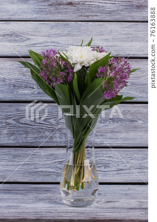 Flowers in transparent vase on wooden background. Flowers in transparent vase on wooden background. 76163888