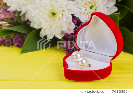 Heart-shaped box with earring and flowers. Heart-shaped box with earring and flowers. 76163934