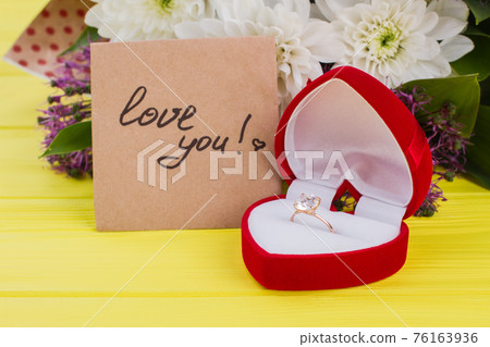 Golden engagement ring in a heart shaped box. 76163936