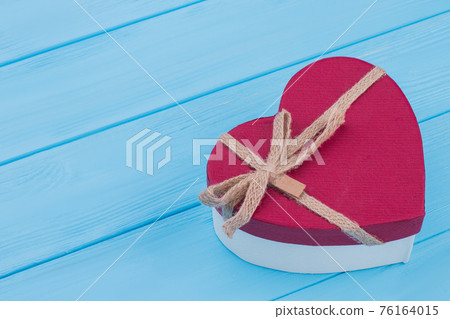 Red heart shaped gift box over blue background. Red heart shaped gift box over blue background. 76164015