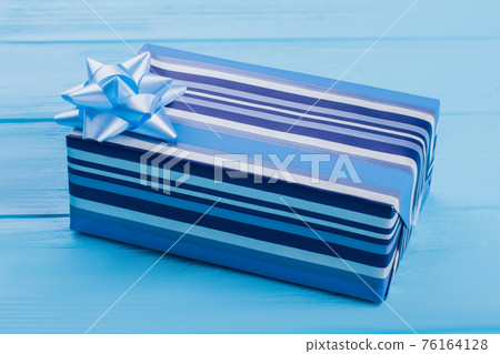Blue gift box on blue wooden surface. Blue gift box on blue wooden surface. 76164128