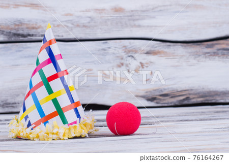 Funny paper hat and clowns red nose. 76164267