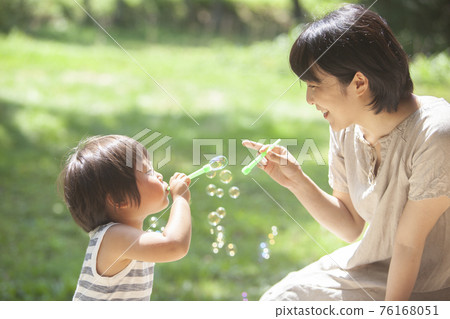 父母和孩子在夏日花園裡玩肥皂泡 76168051