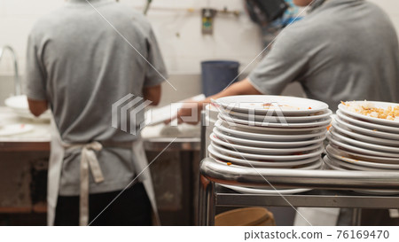 Man washing dish in sink 76169470