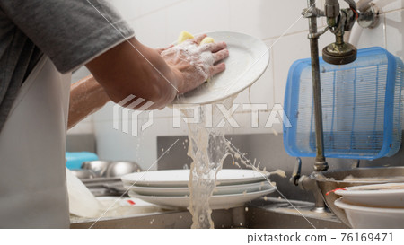 Man washing dish in sink 76169471