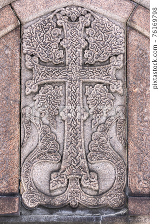 Armenian Christian cross carved in stone. Ancient ornamental christian cross on stone in church Armenian Christian cross carved in stone. Ancient ornamental christian cross on stone in church 76169798