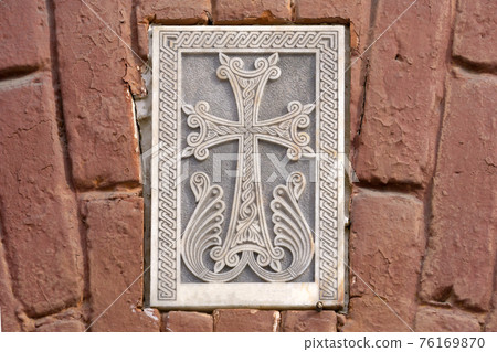Armenian Christian cross carved in stone. Ancient ornamental christian cross on stone in church Armenian Christian cross carved in stone. Ancient ornamental christian cross on stone in church 76169870