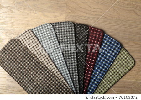 Types and samples of carpets in different colors on wooden floor backgrond. Carpets for rooms, apartments and houses. 76169872