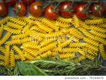 Raw fusilli pasta with tomatoes, herbs and basil. Italian pasta with ingredients in the colors of the Italian flag. 76169879