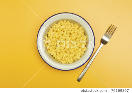Pasta background. Mac and Cheese pasta on a yellow background. American style Italian pasta with cheese. Pasta background. Mac and Cheese pasta on a yellow background. American style Italian pasta with cheese. 76169897
