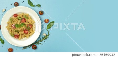 Food pasta on a blue background. Italian fusilli pasta with tomatoes, herbs and basil on a white plate. Healthy food concept. Food pasta on a blue background. Italian fusilli pasta with tomatoes, herbs and basil on a white plate. Healthy food concept. 76169932
