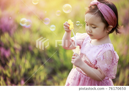 Little girl playing on the park lawn Little girl playing on the park lawn 76170650