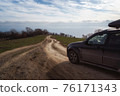 A gravel road leading toward horizon. Spectacular view on the sea and blue sky in the evening. Offroad 4x4 car 76171343
