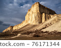 Beautiful white mountain peak lit by sun. White clouds and blue sky on background. Epic rock formation 76171344