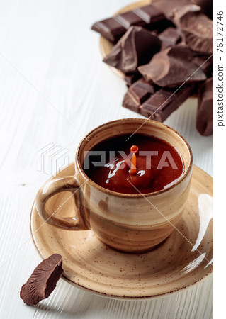 Hot chocolate and broken pieces of bitter chocolate on a white wooden table. Hot chocolate and broken pieces of bitter chocolate on a white wooden table. 76172746