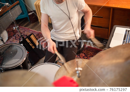 Young man plays drums in home studio close up. 76175297