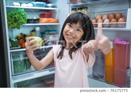asian girl open fridge door drinking a bottle of juice asian girl open fridge door drinking a bottle of juice 76175775