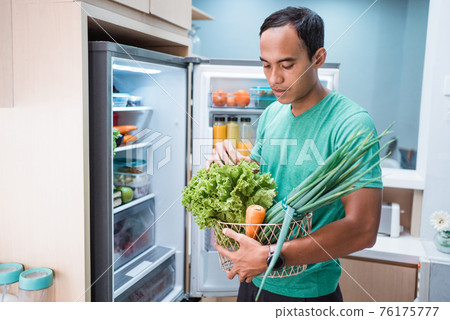 man opening the fridge door looking for food to cook for dinner man opening the fridge door looking for food to cook for dinner 76175777