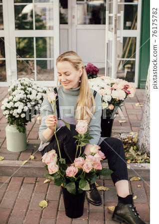 people, business, sale and floristry concept - close up of florist woman holding bunch at flower shop 76175782