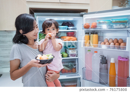 mother carrying her toddler baby and eat fruit together mother carrying her toddler baby and eat fruit together 76175808