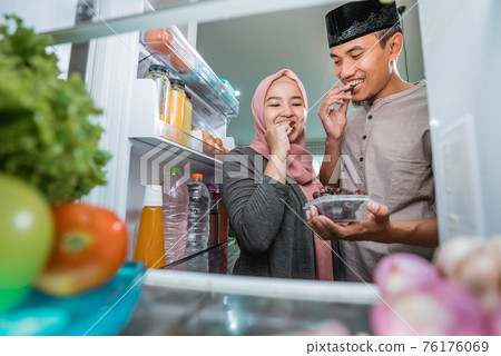 beautiful couple muslim breaking the fast iftar in front of the open fridge 76176069