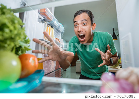 excited young asian man opening the fridge door excited young asian man opening the fridge door 76176095