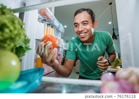 asian man taking ingredient out from the fridge to cook asian man taking ingredient out from the fridge to cook 76176118